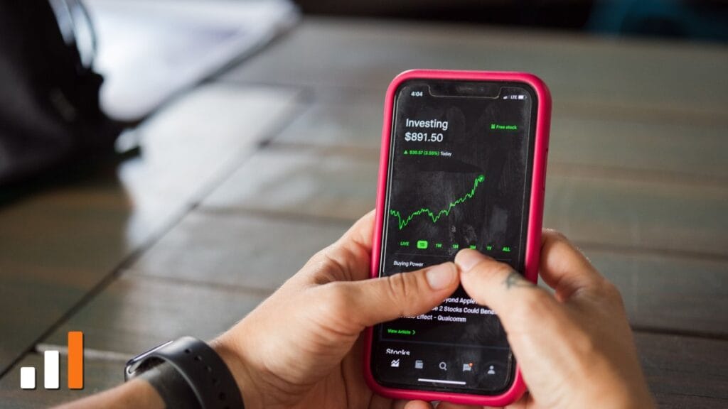 Pessoa segurando smartphone com aplicativo de cotações de mercado