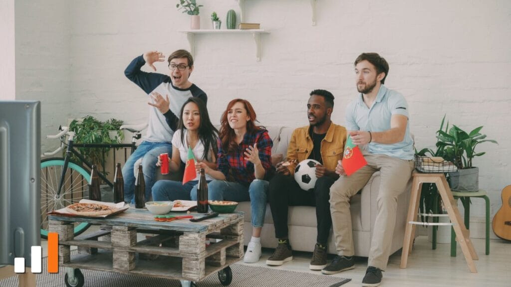 Grupo de amigos comemorando enquanto assiste a um jogo de futebol na televisão