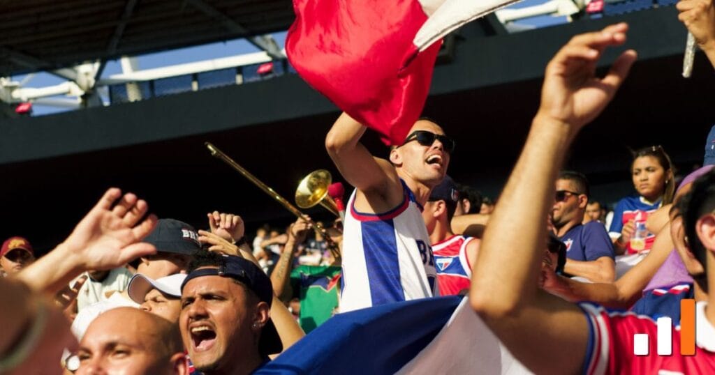 Torcida brasileira vibrando com bandeiras e instrumentos no estádio