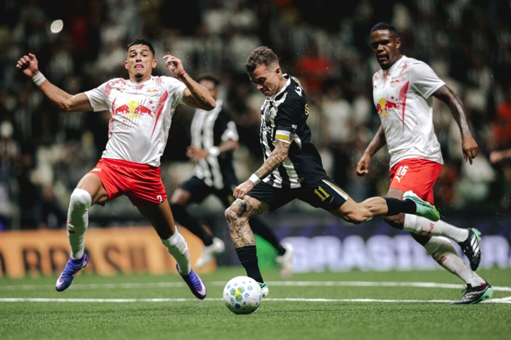 Bernard, camisa 11 do Atlético-MG, chuta a bola entre dois defensores do Red Bull Bragantino na Arena MRV