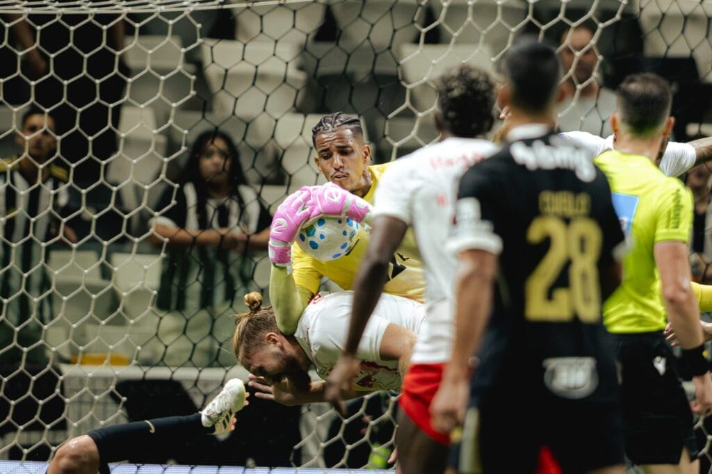 Delfim, goleiro do Atlético-MG de uniforme amarelo e luvas rosa, agarra a bola em lance aéreo entre jogadores do Red Bull Bragantino na Arena MRV