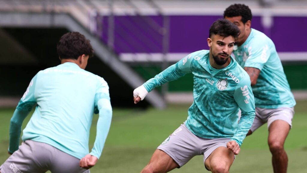 Flaco López, de uniforme de treino verde-água, disputa a bola em atividade do Palmeiras no gramado do Nubank Parque