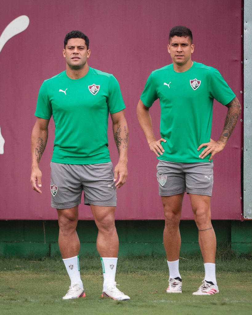 Hulk e um companheiro, de camisa verde de treino, observam a atividade do Fluminense no CT Carlos Castilho