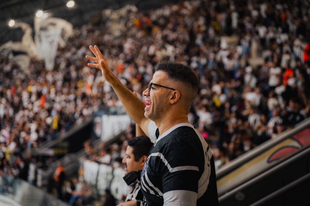 Torcedor do Atlético-MG canta com o braço erguido diante da arquibancada lotada da Arena MRV, em Belo Horizonte