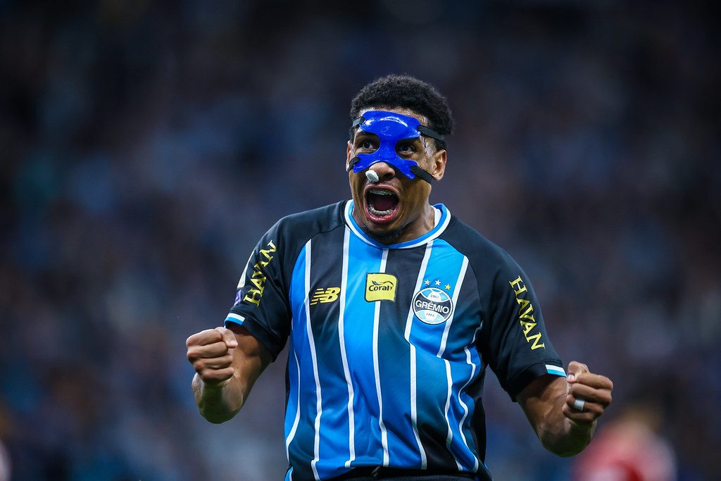 Wallace, zagueiro do Grêmio, de máscara azul, vibra com os punhos cerrados no Gre-Nal na Arena do Grêmio