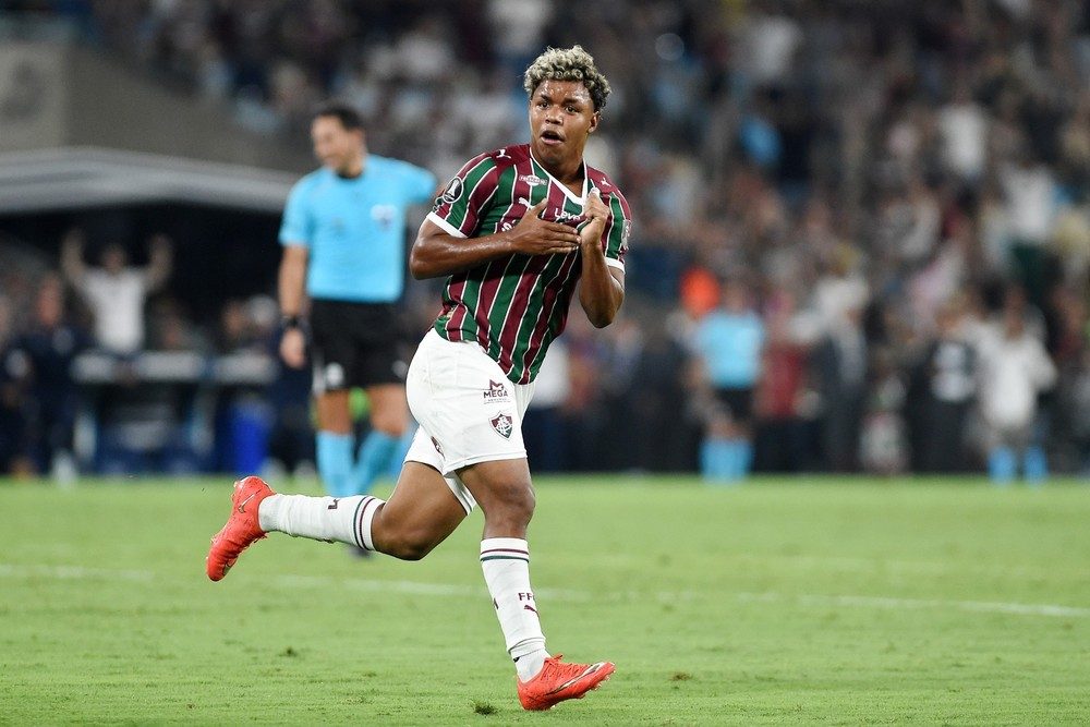 Wesley Natã, de camisa tricolor do Fluminense, corre com as mãos no peito para comemorar o gol no gramado do Maracanã